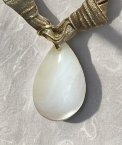 Collier Eloha noué à la main en tissu ocre satiné avec pendentif d’agate rayée naturelle. Bijou artisanal fait main, doux et chaleureux.