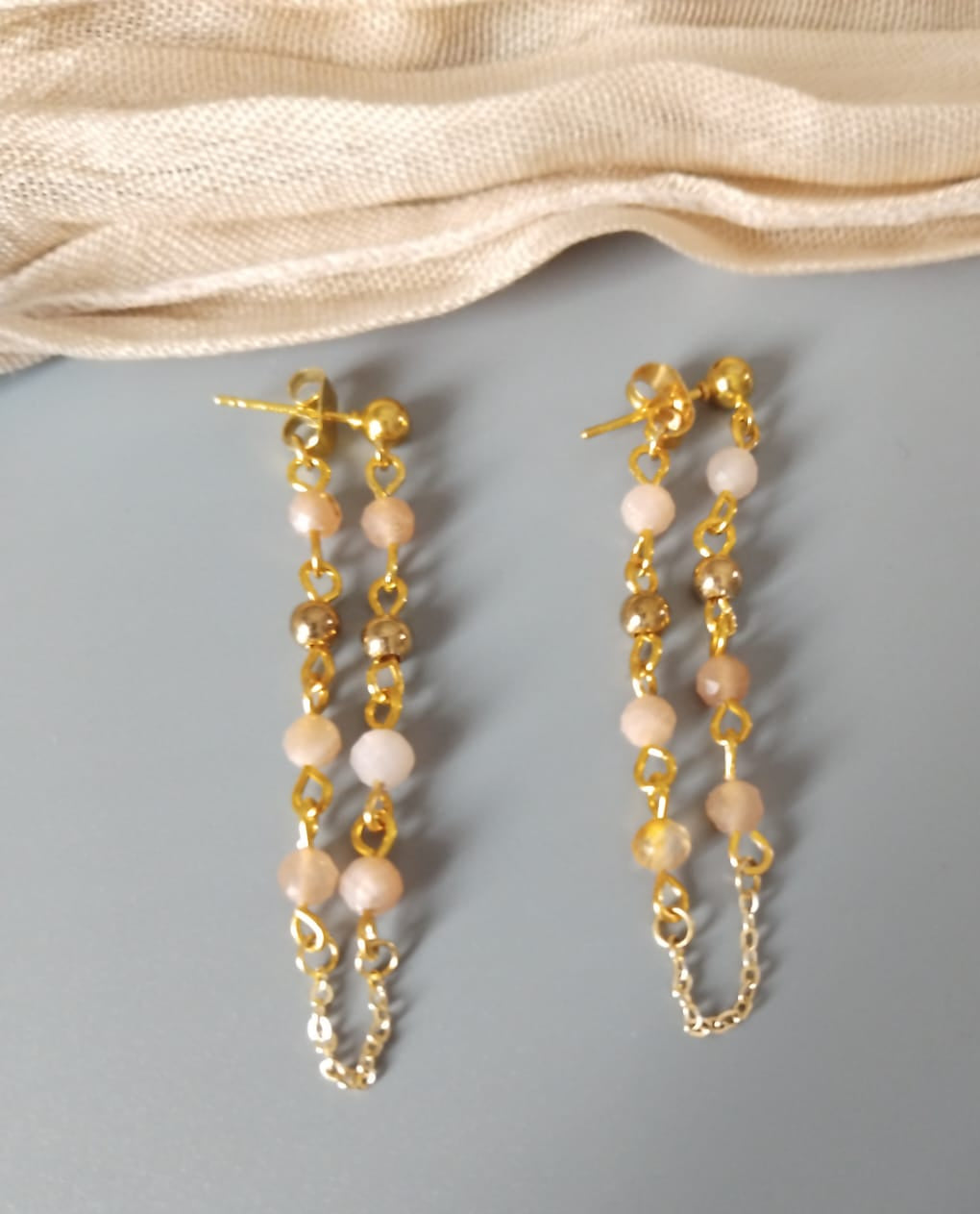 boucles en pierre de soleil et perles dorées reliées au papillon du clou